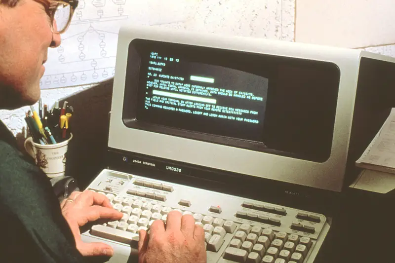 Persona usando un ordenador antiguo con texto en pantalla