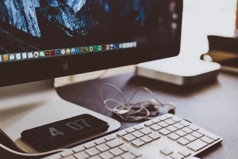 Teclado de aluminio sobre un escritorio, delante de un monitor encendido