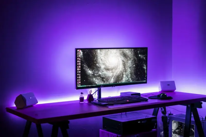 Escritorio con un monitor y un teclado iluminados con luz morada