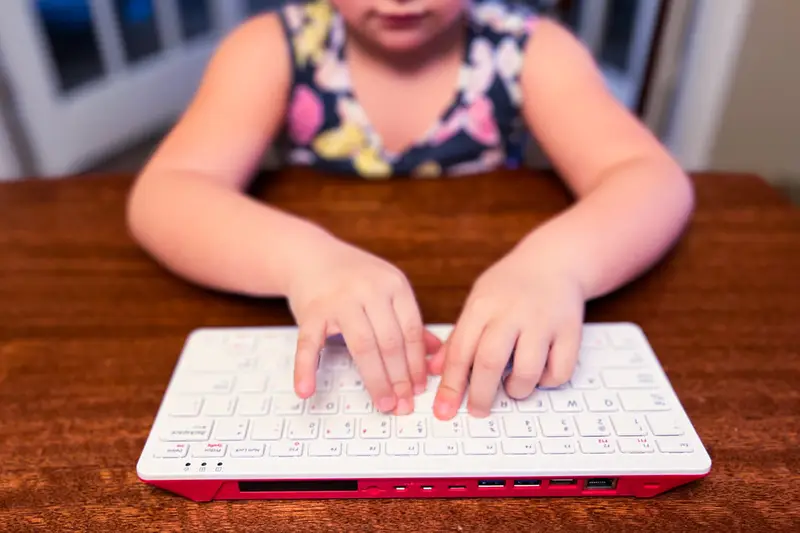 Niña escribiendo en un teclado blanco