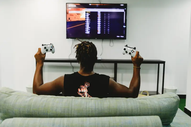 Persona jugando a un videojuego en una pantalla grande desde el sofá