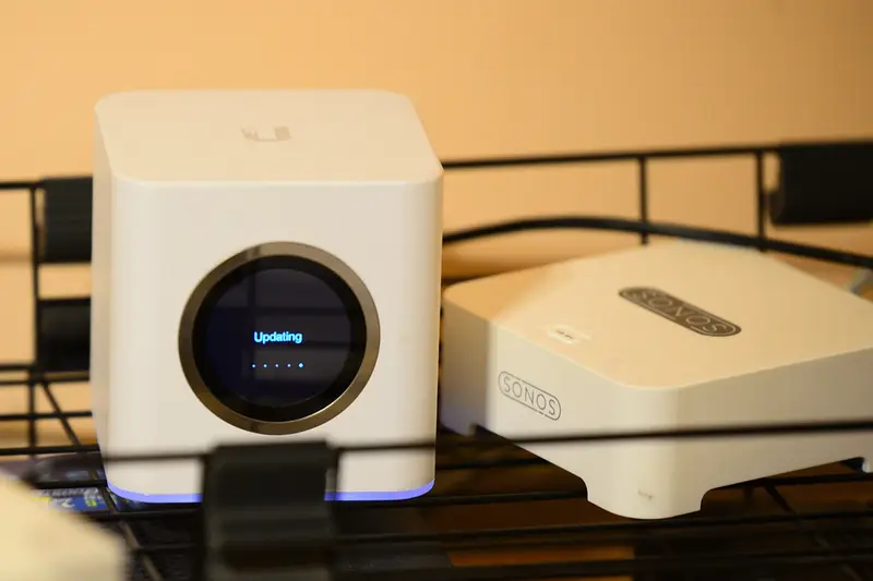 Router Wi-Fi blanco de forma cúbica en una estantería
