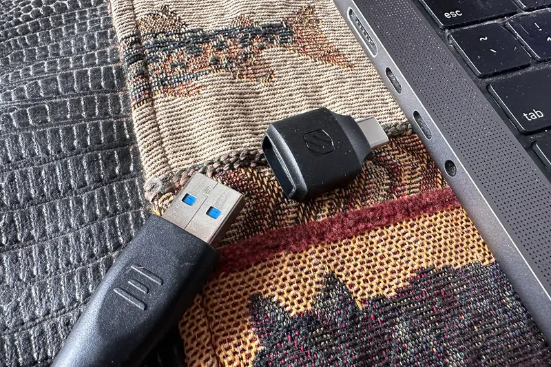 Adaptador USB conectado a un cable junto a un portátil